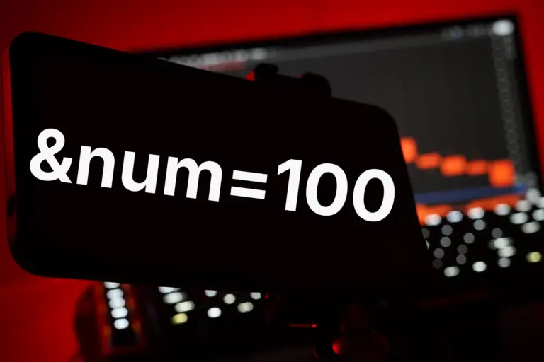 Smartphone mit der Anzeige &num=100 vor einem unscharfen Hintergrund mit Grafiken.