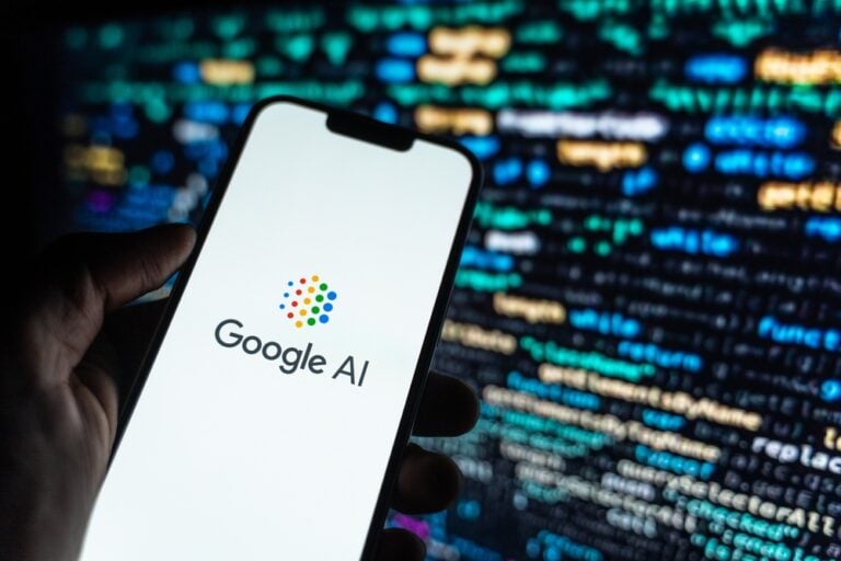 Ein Smartphone zeigt das Google-AI-Logo vor einem unscharfen Code-Hintergrund zur Google AI Performance Report in der Search Console.