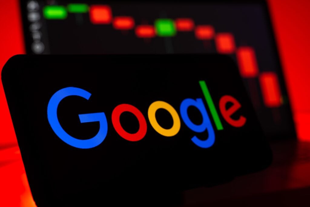 Auf einem schwarzen Display steht das farbige Google-Logo vor einem unscharfen Kursdiagramm mit überwiegend roten Balken; Thema ist AI Max.